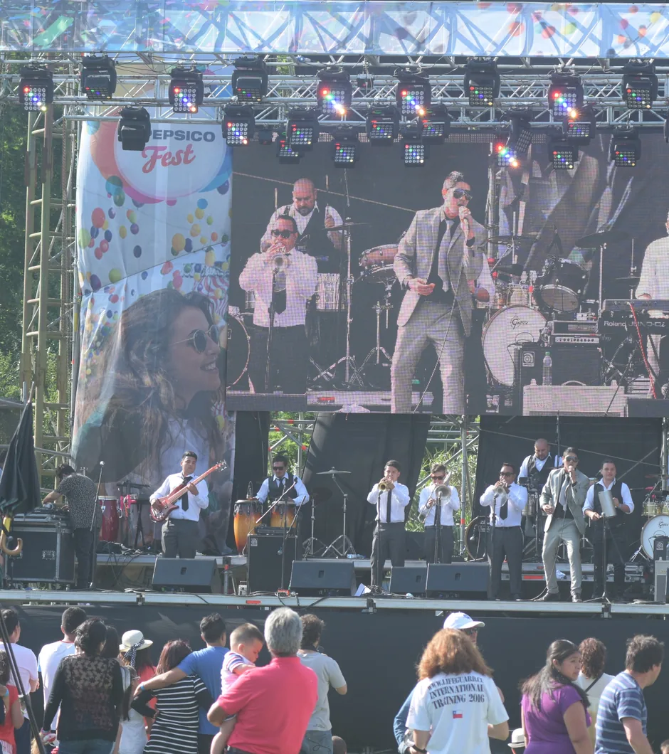 Escenario del PepsiCo Fest con una banda en vivo, pantalla LED y público de pie.