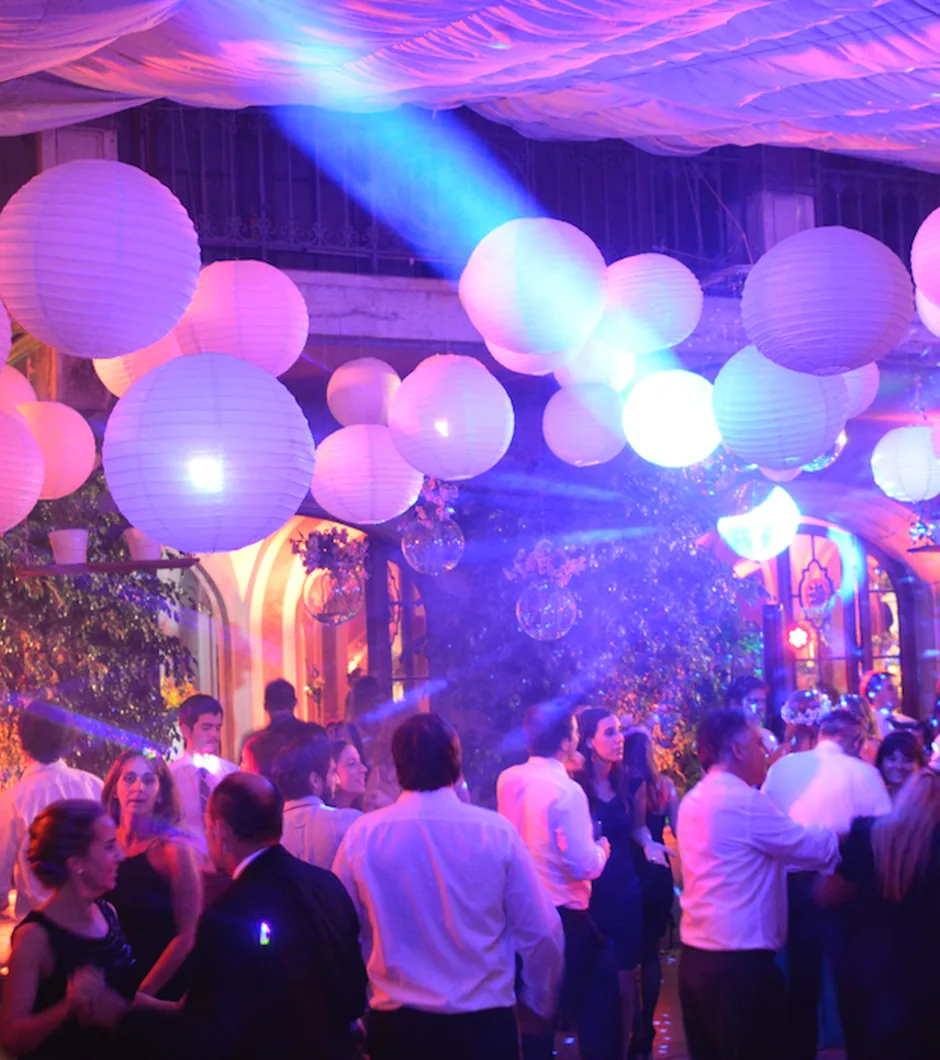 Pista de baile iluminada, con globos de luz colgando sobre los asistentes.